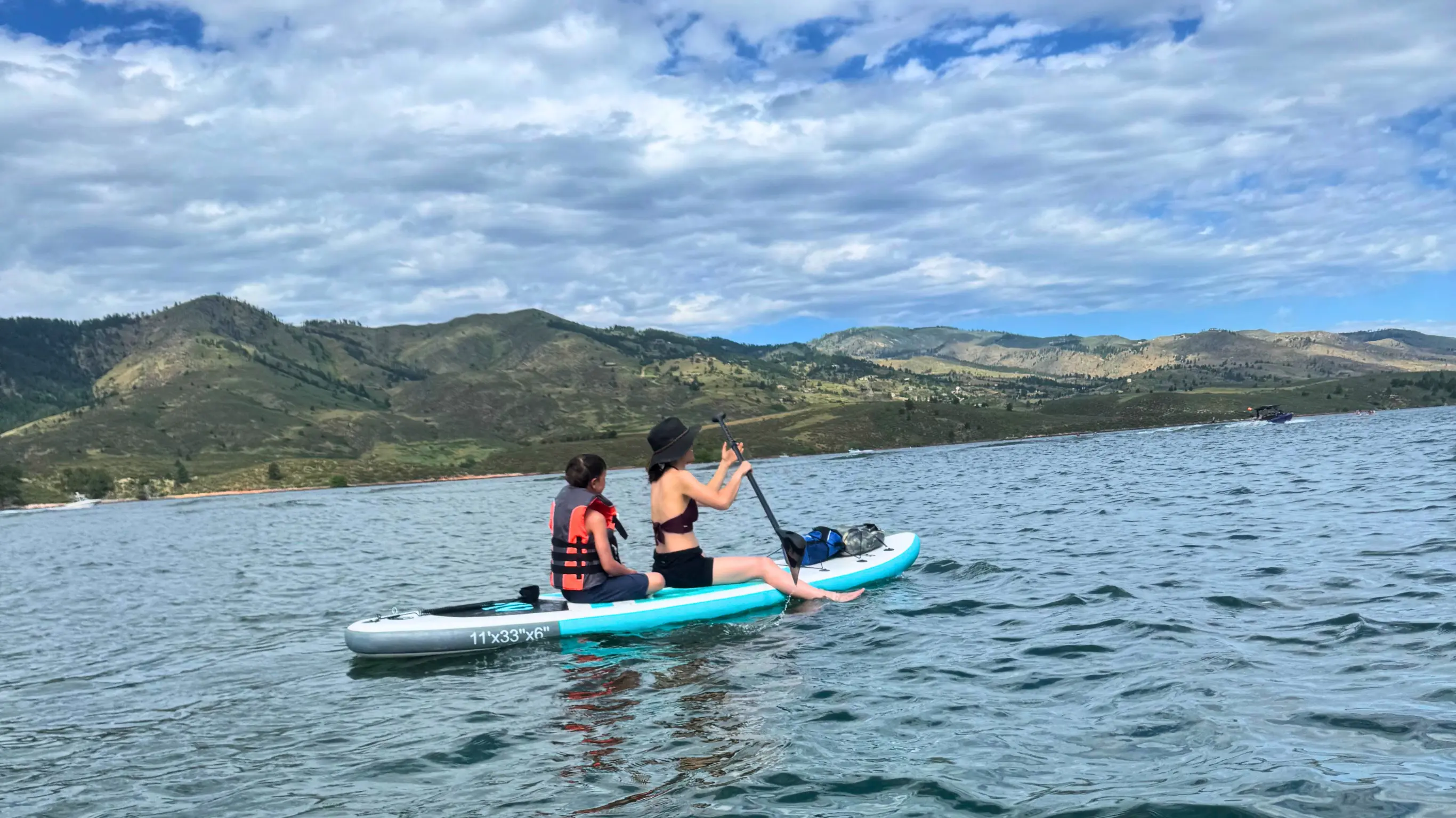 Woman and child paddle boarding together on a lake